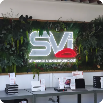 Logo néon lumineux « SVI » avec lèvres rouges, enseigne personnalisée sur mur végétalisé