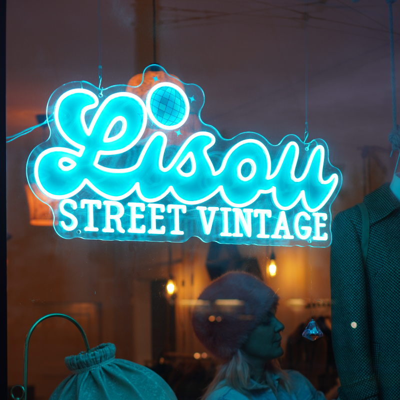 Enseigne néon bleue « Lisou Street Vintage » sur vitrine de boutique de mode rétro