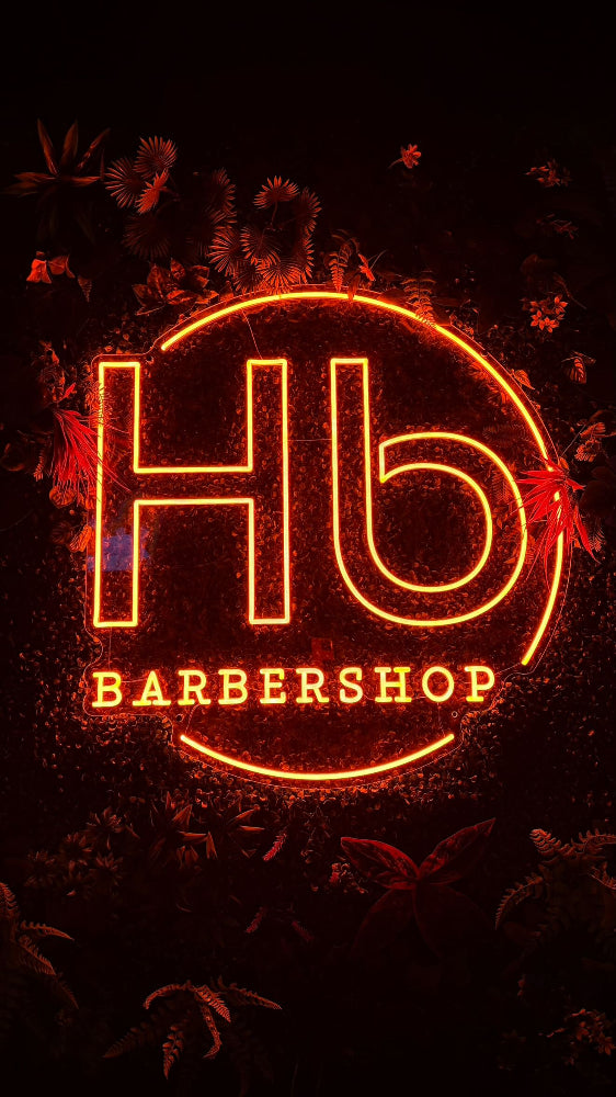 Logo néon rouge HB Barbershop entouré de motifs lumineux