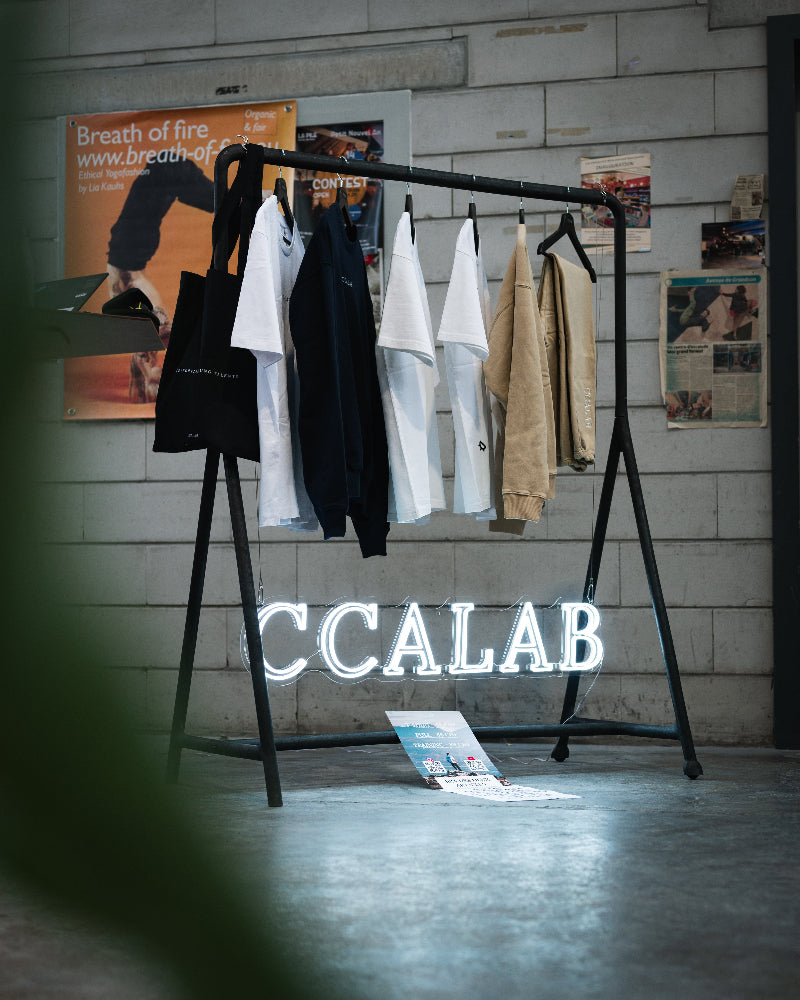 Portants de vêtements dans un showroom avec logo CCALAB en fond